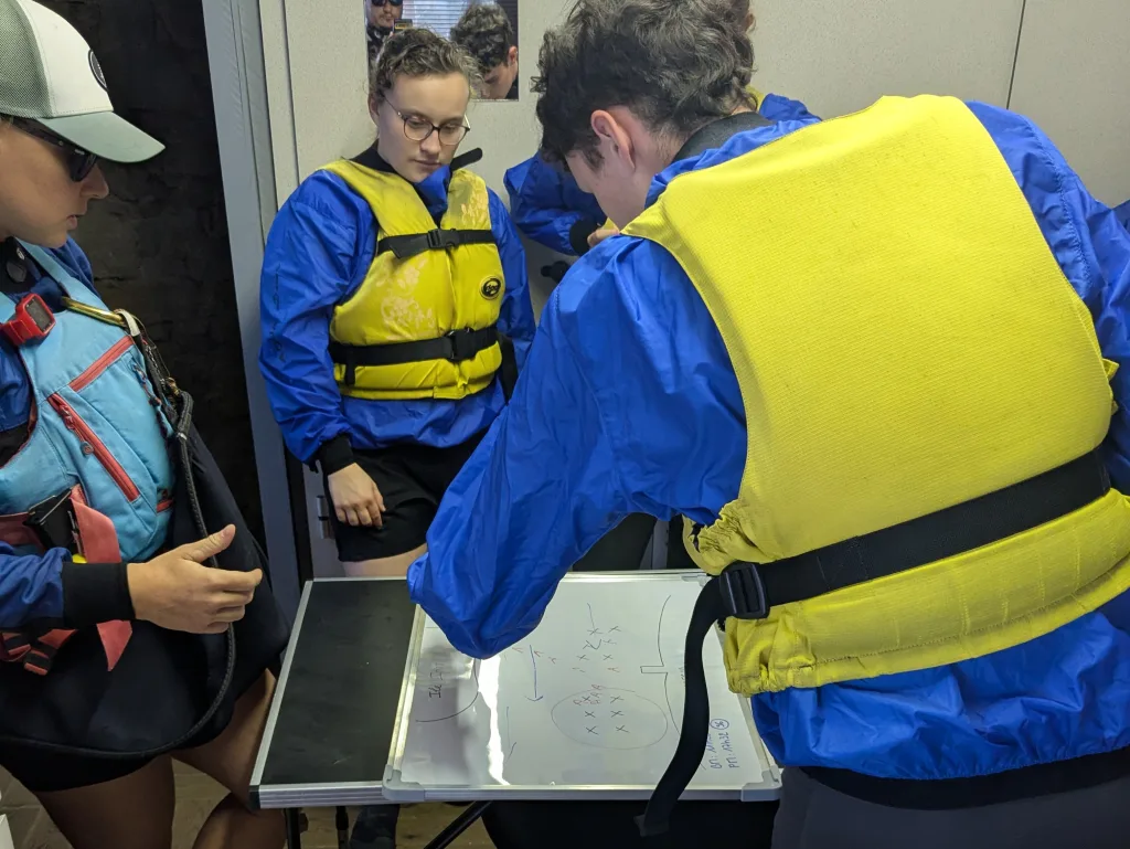 Préparation de la sortie avec des scolaires sur une carte marine lors d'un cycle scolaire kayak.